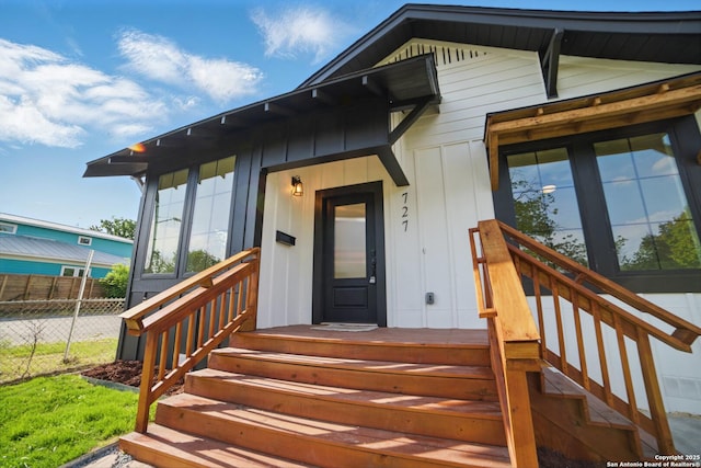 view of exterior entry featuring fence and board and batten siding