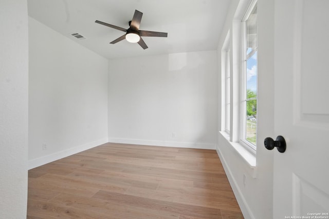 empty room with baseboards, ceiling fan, wood finished floors, and visible vents