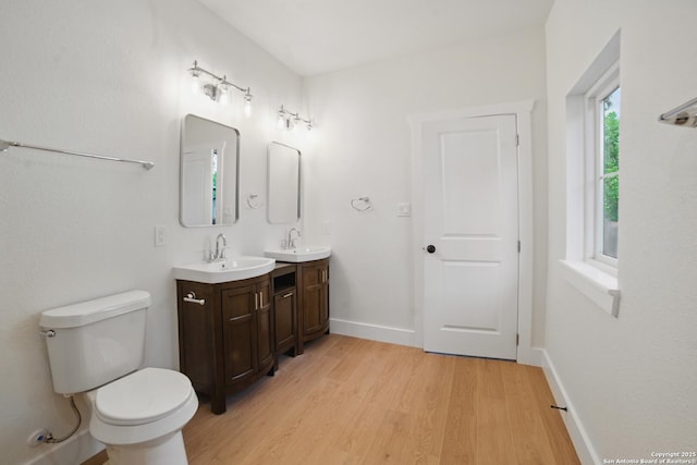 bathroom featuring a sink, double vanity, toilet, and wood finished floors