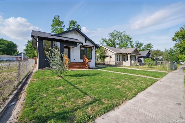 bungalow-style house featuring board and batten siding, central AC unit, fence private yard, and a front yard
