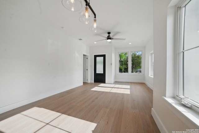 unfurnished living room featuring baseboards, visible vents, ceiling fan with notable chandelier, and light wood-style floors