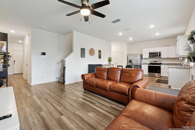 living room with light wood-style floors, a ceiling fan, baseboards, recessed lighting, and visible vents