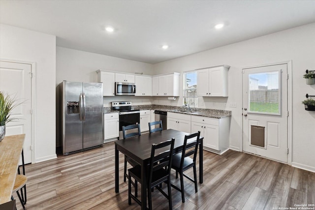 kitchen featuring a sink, appliances with stainless steel finishes, wood finished floors, and white cabinets