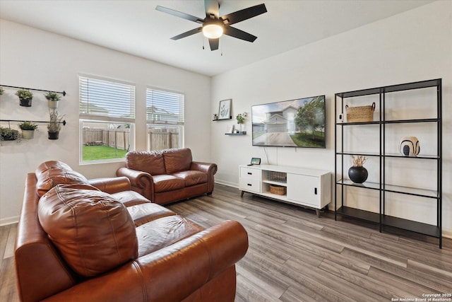 living area featuring baseboards, ceiling fan, and wood finished floors
