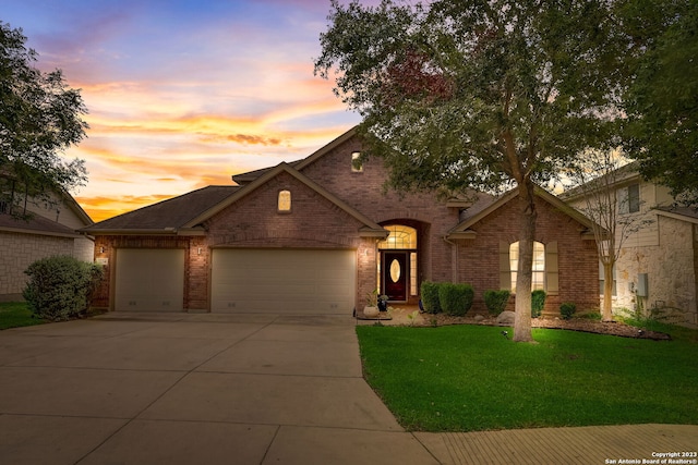 view of front of house featuring roof with shingles, an attached garage, brick siding, concrete driveway, and a yard