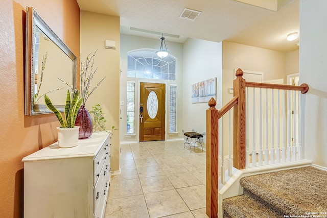 entrance foyer featuring light tile patterned floors, baseboards, stairs, and visible vents