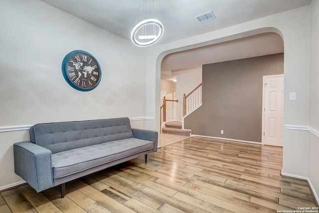 living area with visible vents, arched walkways, hardwood / wood-style floors, and stairway