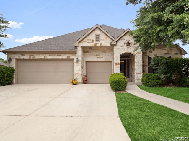 view of front of house featuring roof with shingles, stone siding, a garage, a front yard, and driveway