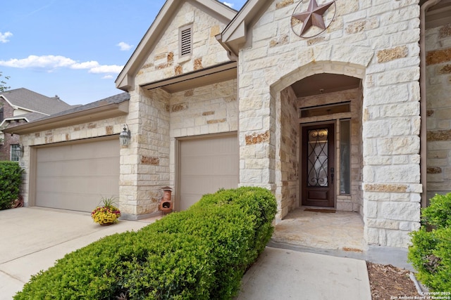 entrance to property with a garage, driveway, and stone siding