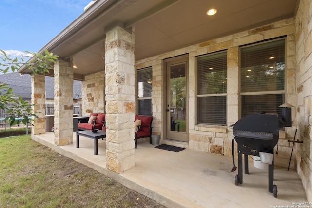 view of exterior entry featuring a patio, a porch, and stone siding