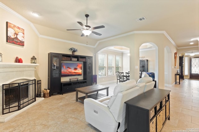 living area with visible vents, arched walkways, ceiling fan, and crown molding