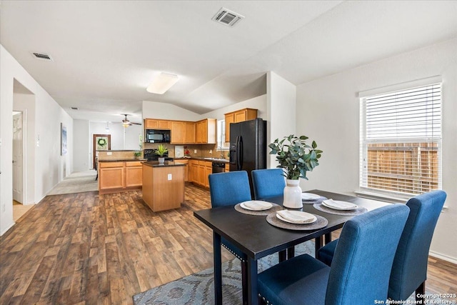 dining space featuring a ceiling fan, lofted ceiling, wood finished floors, and visible vents