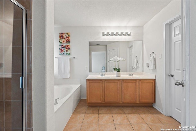 bathroom with a garden tub, double vanity, tile patterned floors, a sink, and a stall shower