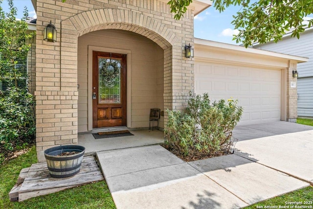 entrance to property featuring concrete driveway, brick siding, and a garage