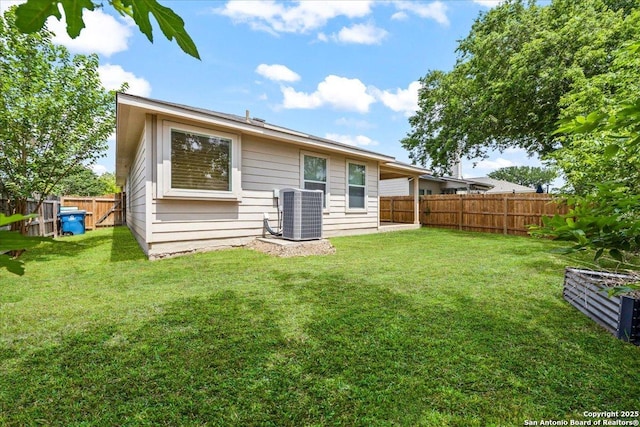 rear view of house featuring a fenced backyard, central AC unit, and a yard