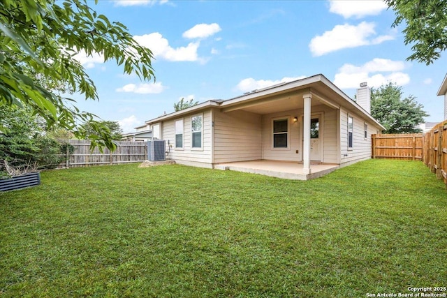 back of property with a fenced backyard, central AC unit, a chimney, a patio area, and a yard