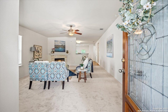 carpeted dining area with ceiling fan and a warm lit fireplace