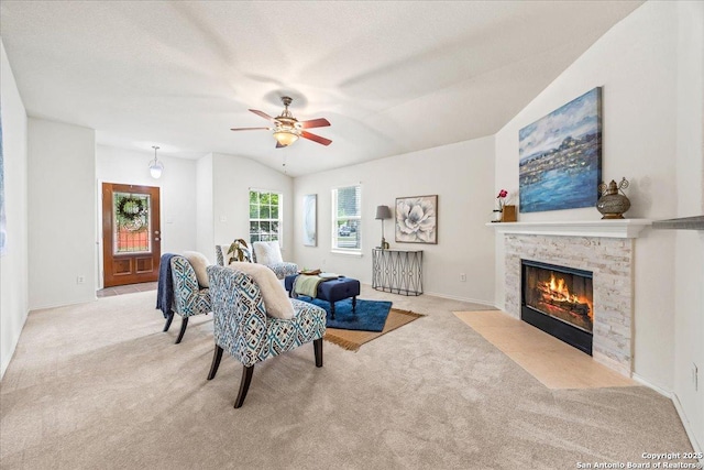 living area with a ceiling fan, light carpet, lofted ceiling, and a fireplace