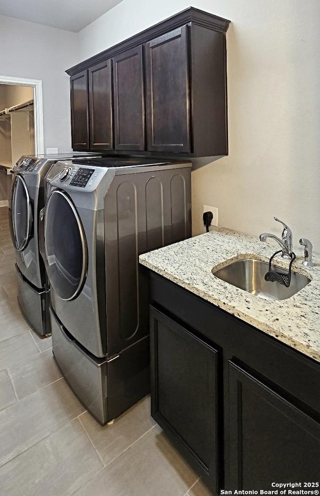 clothes washing area featuring a sink, light tile patterned floors, cabinet space, and washer and dryer