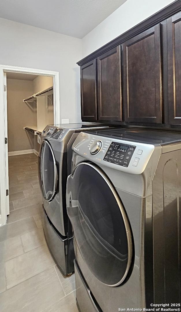 clothes washing area featuring washer and dryer and cabinet space