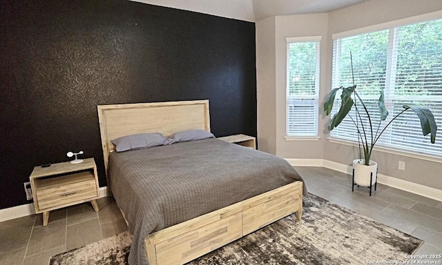 bedroom featuring baseboards, tile patterned floors, and multiple windows