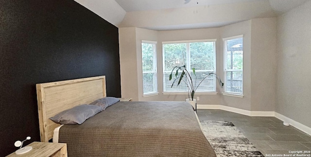 bedroom featuring baseboards, multiple windows, and dark tile patterned floors