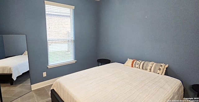 bedroom with tile patterned floors, multiple windows, and baseboards