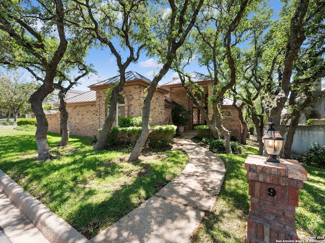 9 Chester Downs, San Antonio, TX 78257 - view of front of home featuring brick siding, a standing seam roof, metal roof, and a front lawn