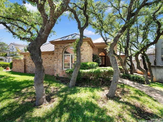 9 Chester Downs, San Antonio, TX 78257 - view of front facade featuring a standing seam roof, metal roof, brick siding, and a front yard