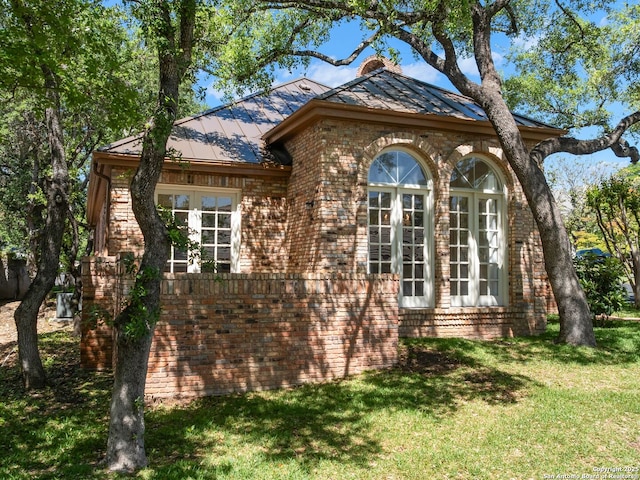 9 Chester Downs, San Antonio, TX 78257 - view of property exterior with french doors, a standing seam roof, brick siding, metal roof, and a lawn