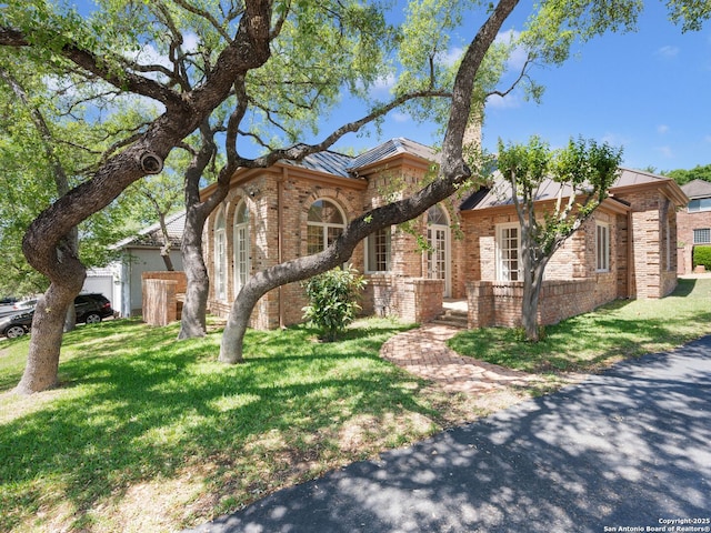 9 Chester Downs, San Antonio, TX 78257 - view of front facade featuring a standing seam roof, a front yard, metal roof, and brick siding