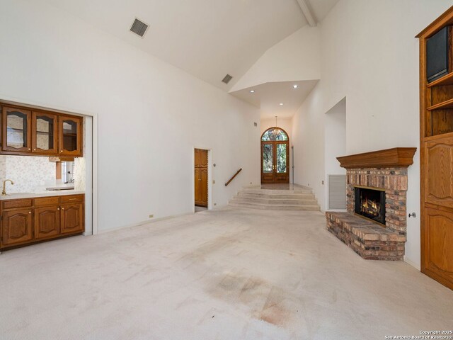 9 Chester Downs, San Antonio, TX 78257 - unfurnished living room with light carpet, a sink, a brick fireplace, high vaulted ceiling, and visible vents