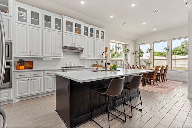 kitchen featuring visible vents, light countertops, gas stovetop, under cabinet range hood, and a sink