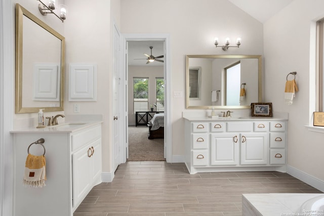 ensuite bathroom featuring ceiling fan, two vanities, a sink, baseboards, and ensuite bathroom