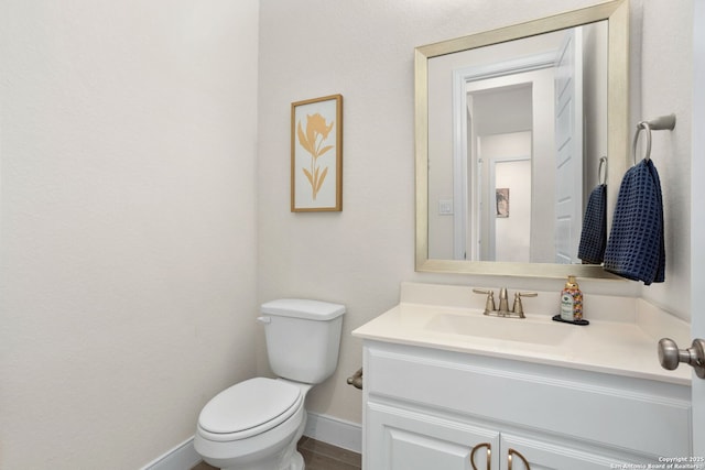 half bathroom with toilet, baseboards, and vanity