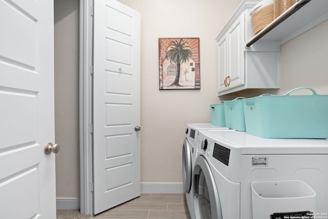 washroom with baseboards, wood finish floors, cabinet space, and washing machine and clothes dryer