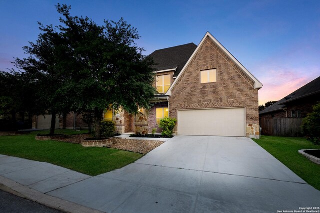 traditional-style house with driveway, a front yard, brick siding, fence, and an attached garage