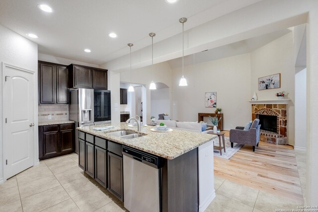 kitchen with a sink, open floor plan, decorative backsplash, light tile patterned floors, and stainless steel dishwasher