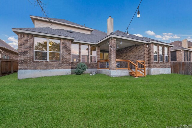 back of property featuring brick siding, a lawn, and fence private yard