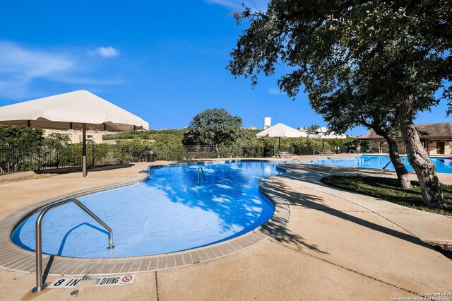 community pool featuring fence and a patio area