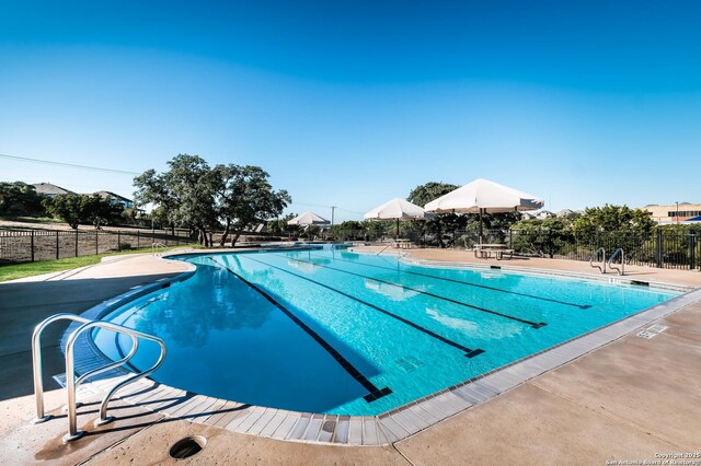 community pool with fence and a patio