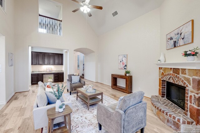 living room featuring arched walkways, light wood finished floors, a ceiling fan, and high vaulted ceiling