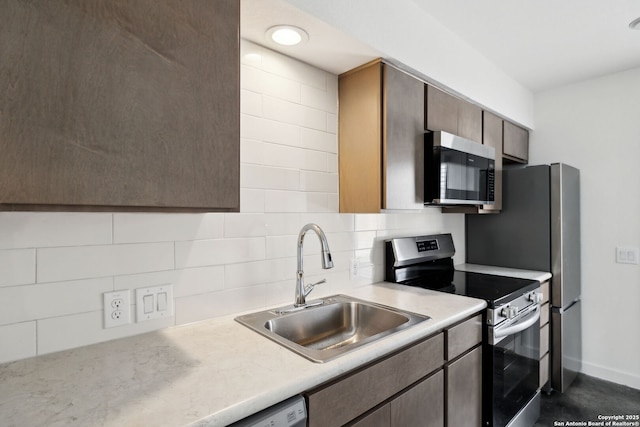 kitchen with a sink, appliances with stainless steel finishes, tasteful backsplash, and light countertops
