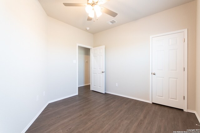 unfurnished bedroom with visible vents, a ceiling fan, dark wood finished floors, and baseboards