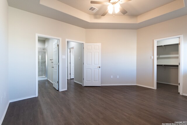3436-3438 Scott Cir, Seguin, TX 78155 - unfurnished bedroom featuring dark wood-style flooring, a walk in closet, baseboards, a tray ceiling, and visible vents