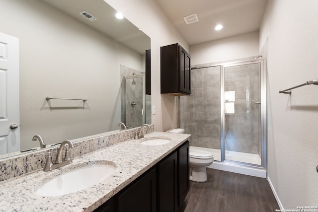 bathroom featuring visible vents, a sink, toilet, and a shower stall