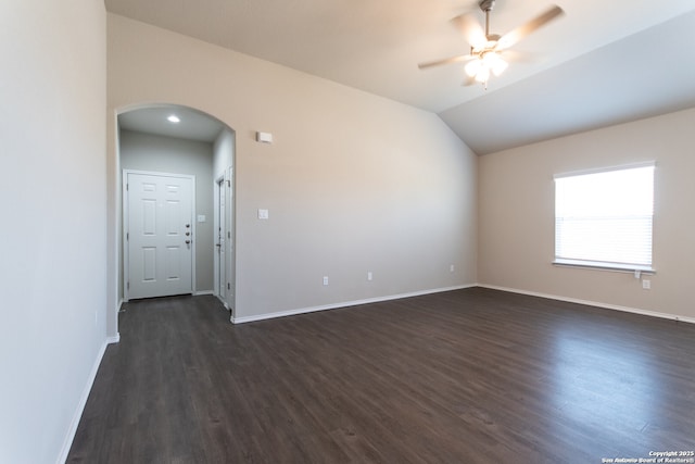 spare room featuring arched walkways, baseboards, a ceiling fan, and dark wood finished floors
