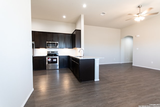 kitchen featuring ceiling fan, arched walkways, a sink, baseboards, and stainless steel appliances