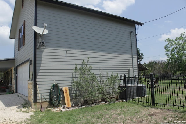 view of home's exterior with fence, an attached garage, and a lawn
