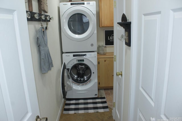 laundry area featuring stacked washing maching and dryer, baseboards, and cabinet space